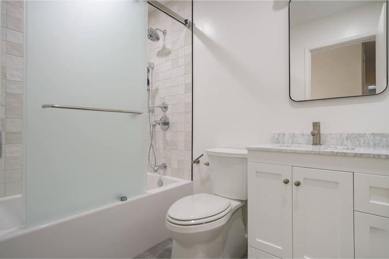 bathroom after: frameless glass tub shower enclosure with marble countertop and ceramic subway tile, by ASL Remodeling, Los Gatos.
