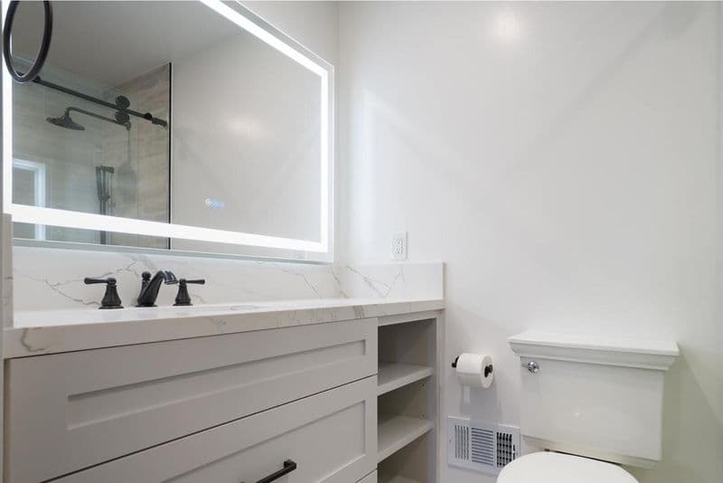 bathroom after: LED backlit mirror over marble vanity with white quartz marble countertop and white shaker cabinetry, by ASL Remodeling, Los Gatos.