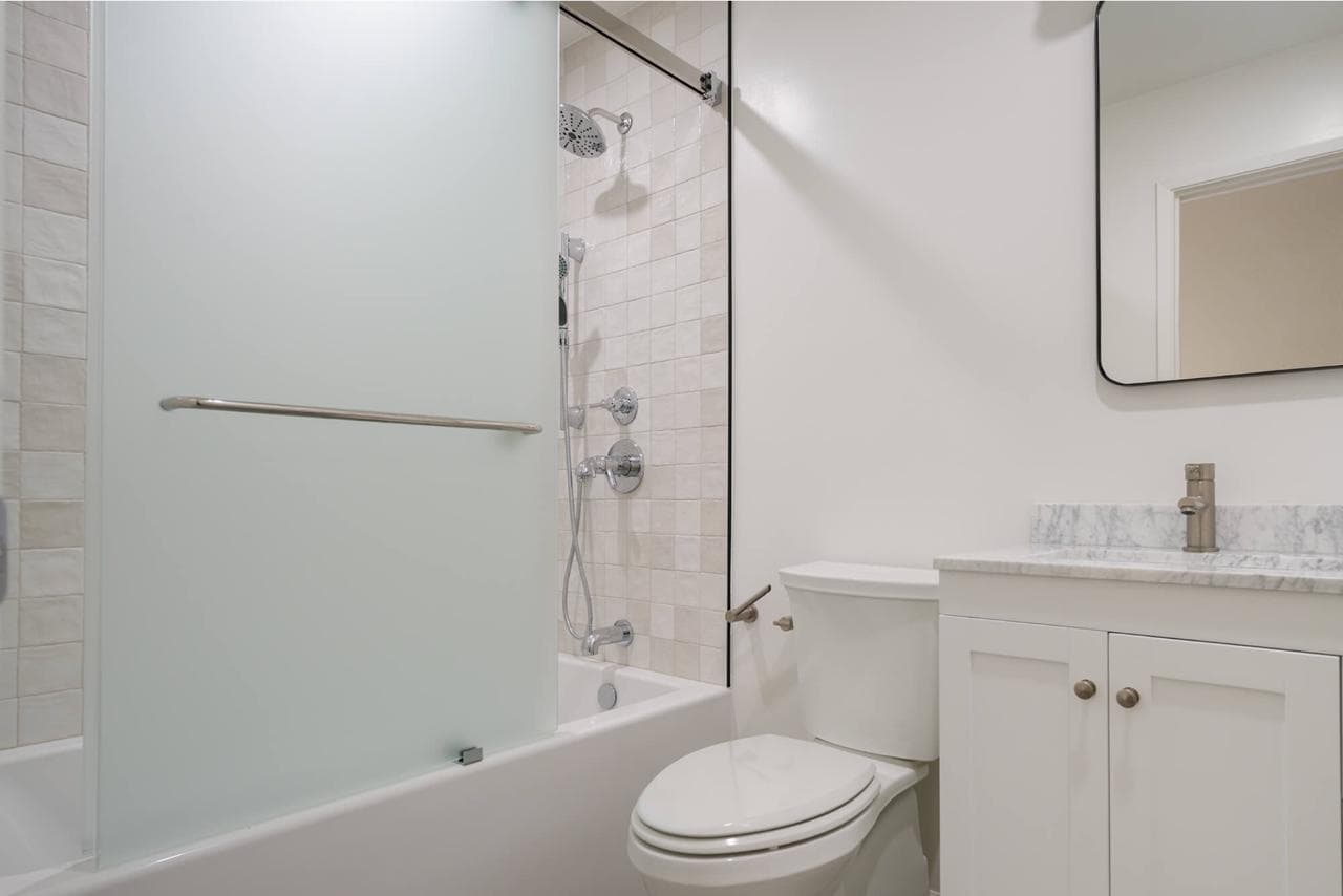 Kitchen and bath remodeling expertise delivers accessible traditional bathroom with tub-shower combo, safety grab bars, white vanity with quartz countertops, and slip-resistant flooring.
