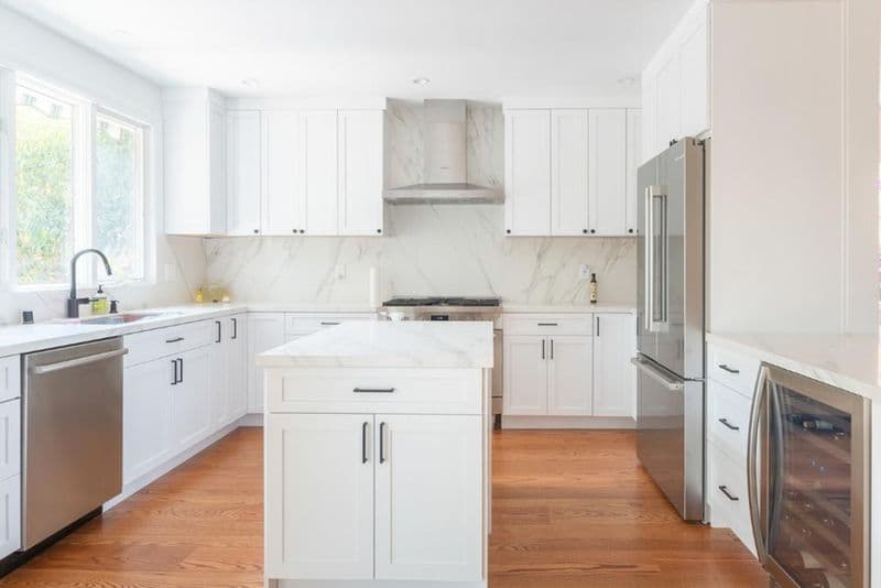 kitchen: marble slab backsplash with custom range hood with marble slab and white shaker cabinets, by ASL Remodeling, San Mateo.