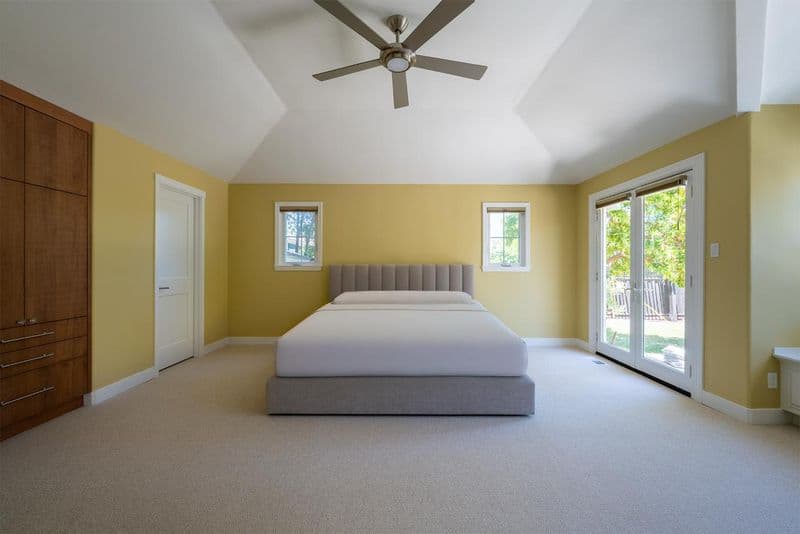 Upgraded master bedroom in Monte Sereno featuring modern ceiling fan, smooth Level 4 wall texture, and two-tone painted walls with natural light