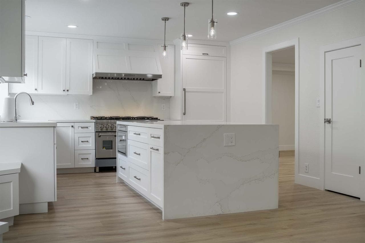 Whole home remodel featuring open floor plan kitchen with large white island, pendant lighting, and white cabinetry throughout.