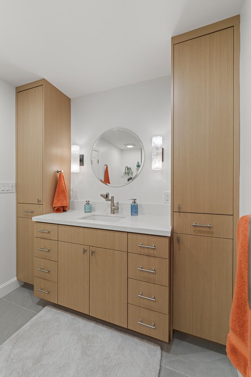 bathroom after: floor to ceiling wood tone vanity with linen towers with light oak laminate cabinetry and white quartz countertop, by ASL Remodeling, Pacifica.