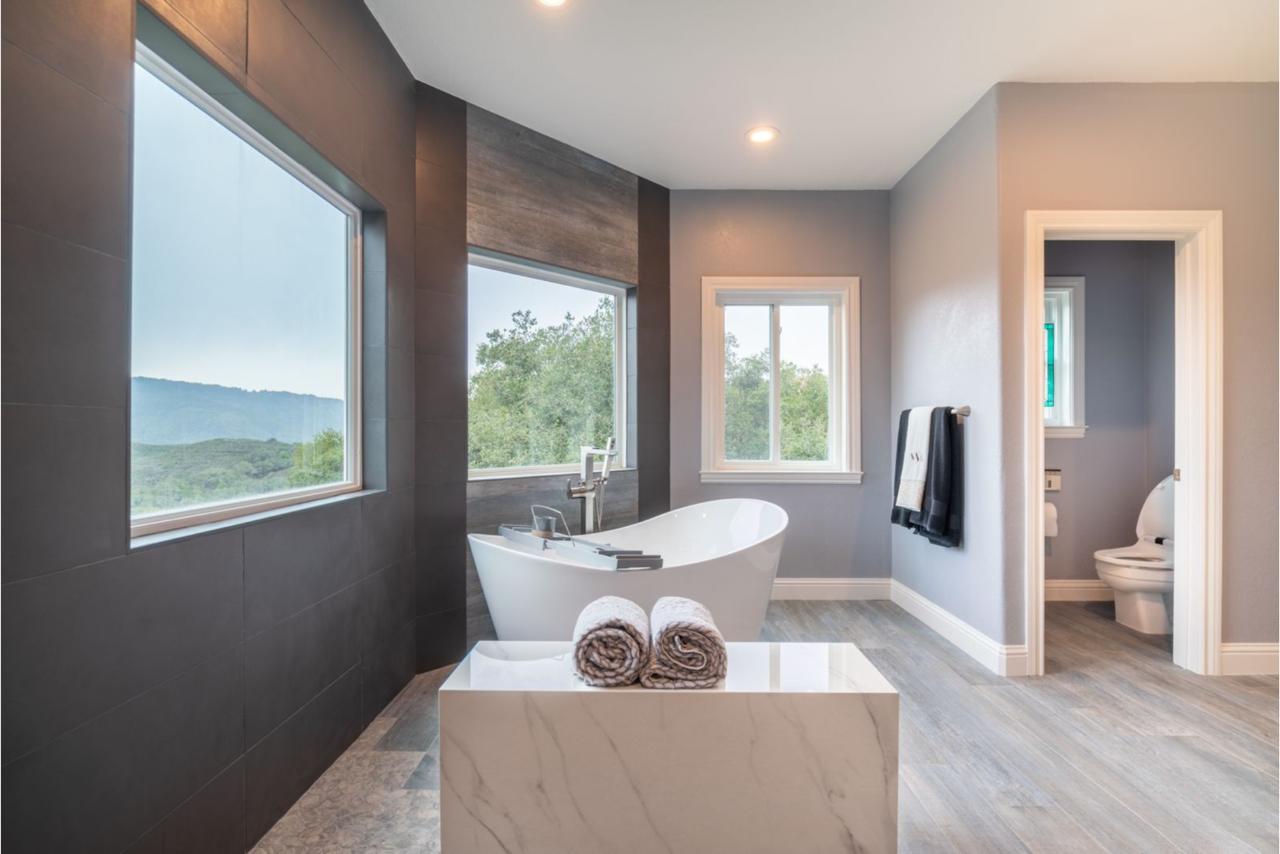 Stunning bathroom remodeling showcasing contemporary design with sculptural freestanding tub positioned by expansive windows to capture breathtaking scenic views and abundant natural light.