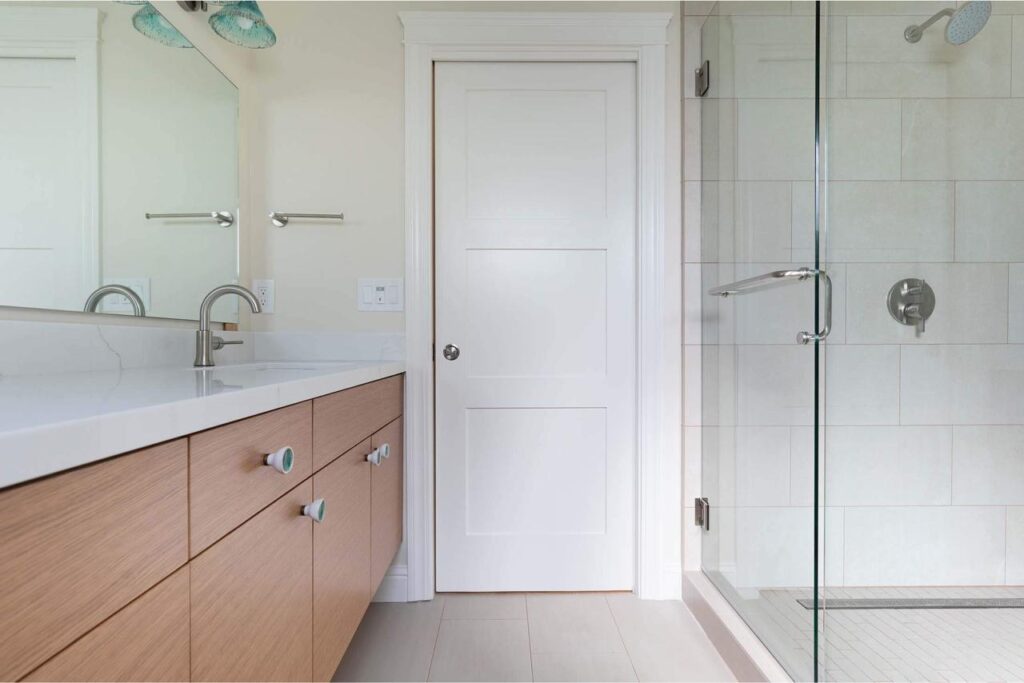 Comprehensive bathroom remodeling services delivered transitional warmth with custom wood floating vanity, white quartz countertops, and seamless frameless glass shower.