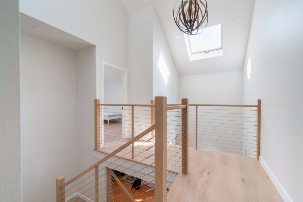 Vista Del Mar upstairs landing in Los Gatos with modern cable railing, skylight, engineered white oak hardwood flooring, and bright natural light