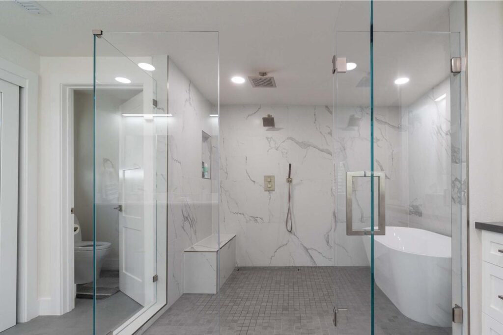 Contemporary bathroom addition by home addition contractors in Los Gatos featuring frameless walk-in shower with white marble tile, floating vanity, and modern fixtures.