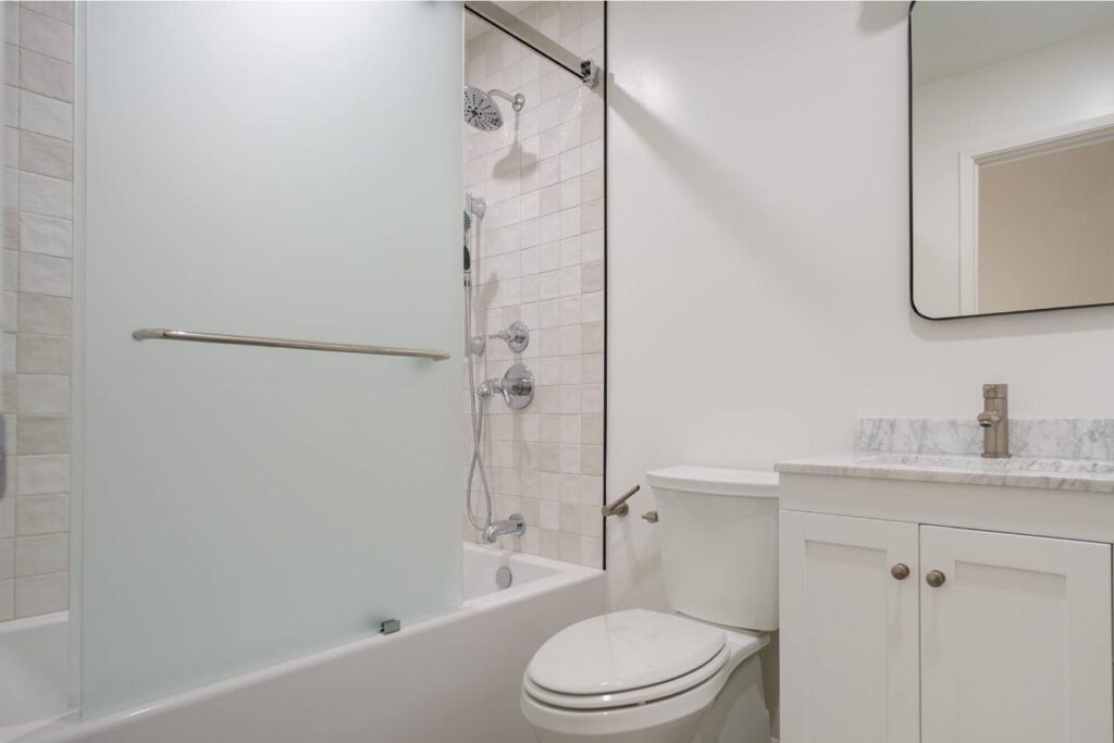 Kitchen and bath remodeling expertise delivers accessible traditional bathroom with tub-shower combo, safety grab bars, white vanity with quartz countertops, and slip-resistant flooring.