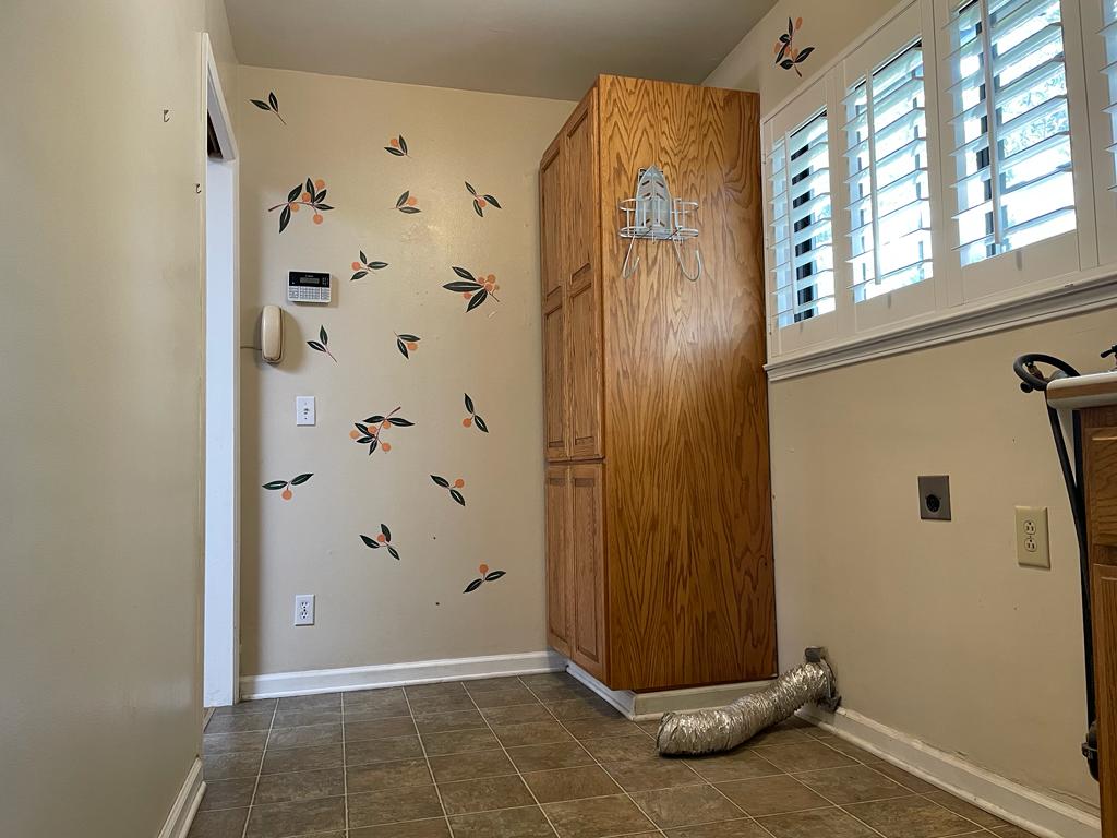 Shulman Ave home remodel laundry room before transformation showing original oak cabinetry and decorative wallpaper prior to layout redesign with custom storage