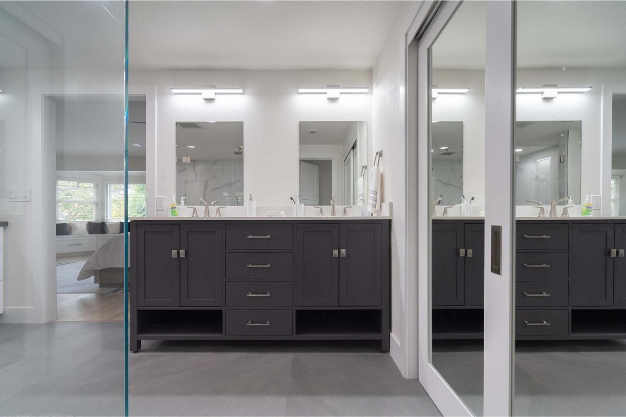 Professional bathroom renovation contractors created contemporary elegance with dark double floating vanity, white quartz countertops, and frameless glass shower enclosure.