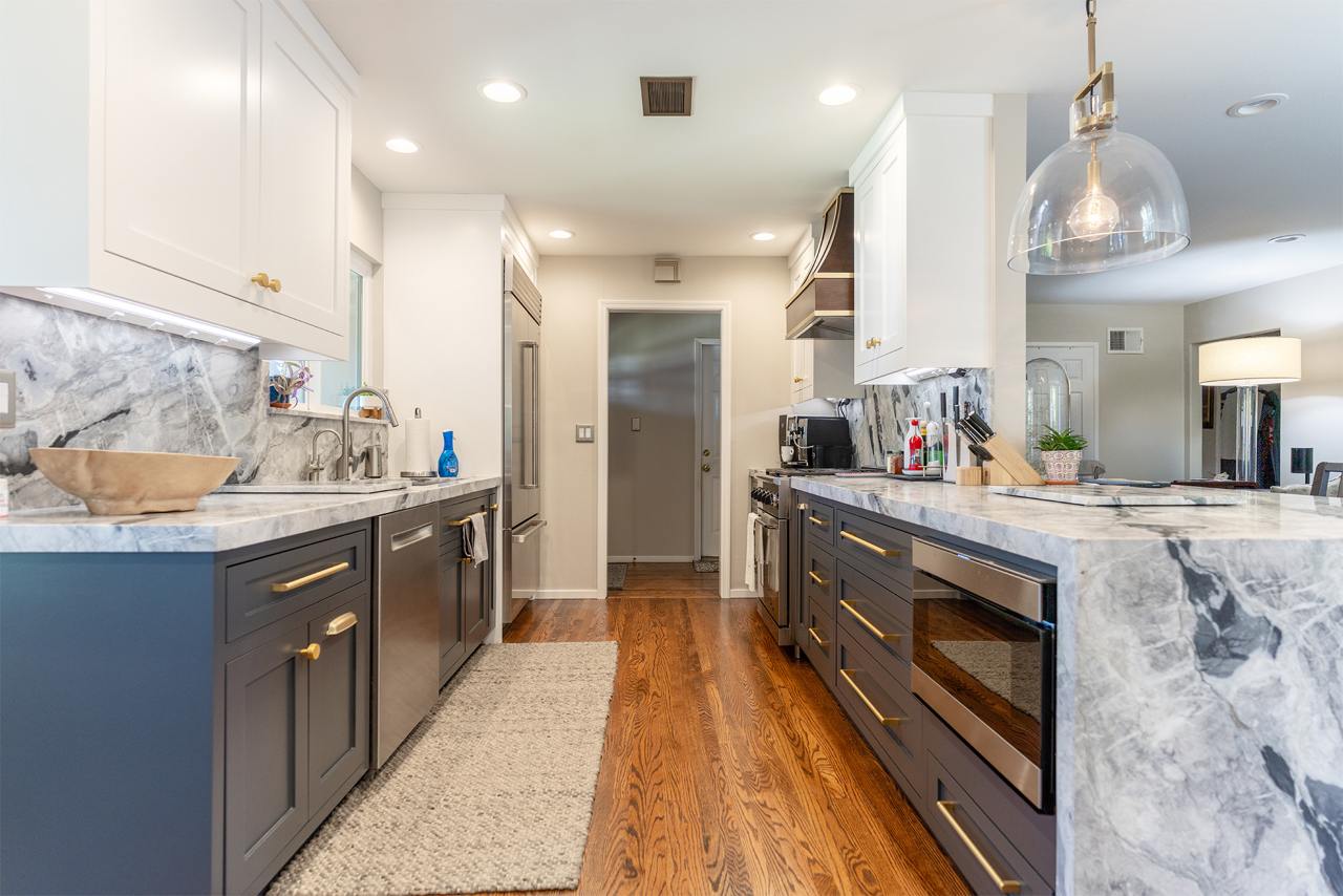 Transitional kitchen showcasing dark wood cabinets, light countertops, professional gas range, and honey-toned hardwood flooring
