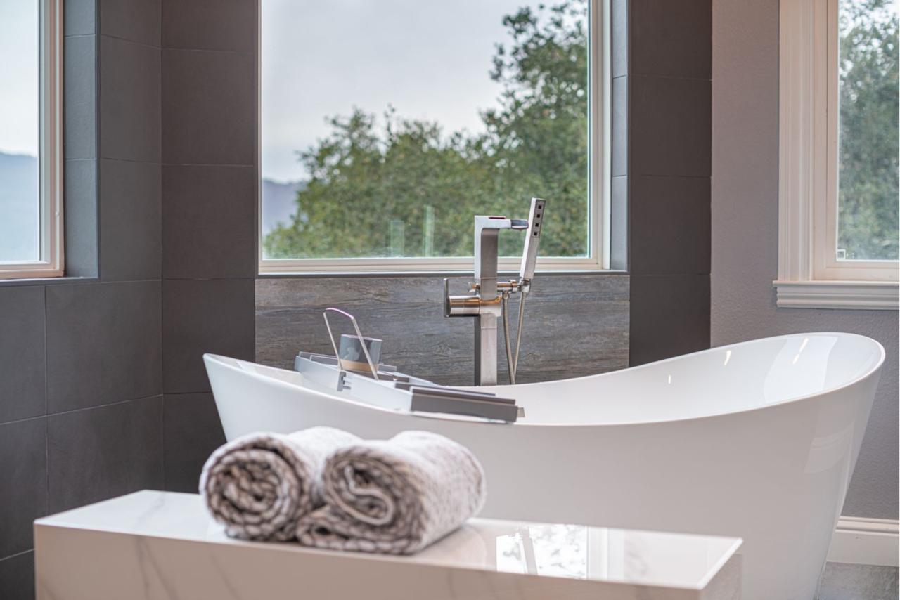 Luxurious spa bathroom showcasing second story addition cost value in Los Gatos with elegant freestanding tub, abundant natural light, and contemporary design elements.